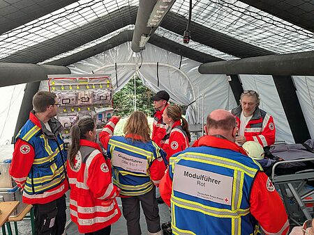 DRK Einsatzkräfte stehen in einem Behandlungszelt