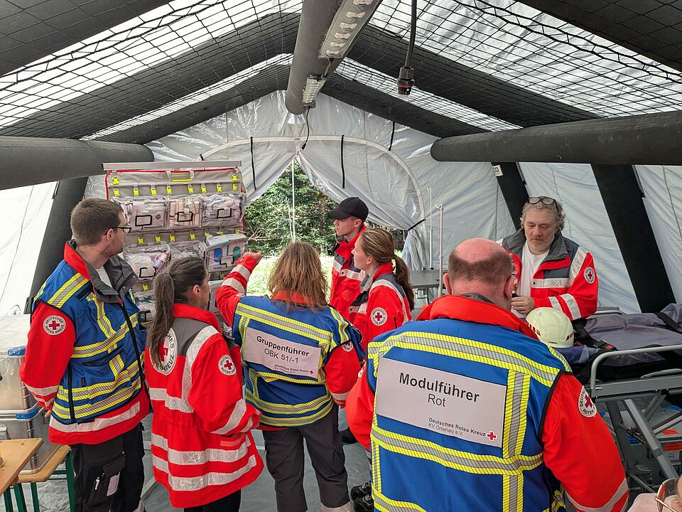 DRK Einsatzkräfte stehen in einem Behandlungszelt