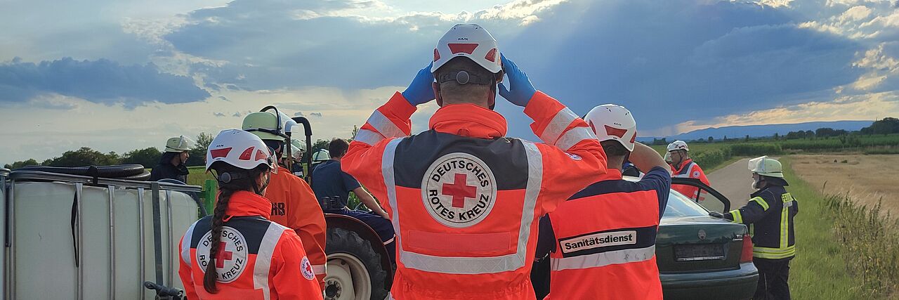 Drei DRK Einsatzkräfte leisten medizinische Hilfe bei einem Verkehrsunfall. 