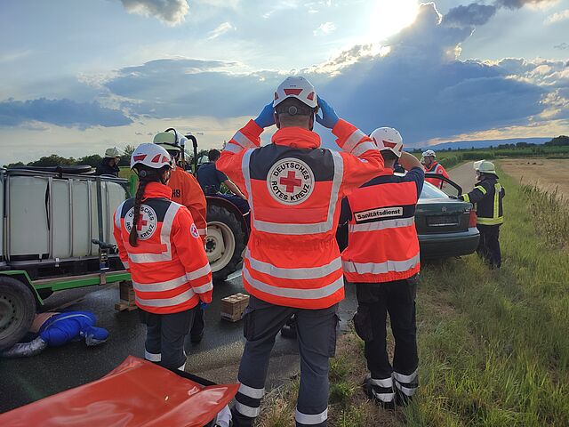 Drei DRK Einsatzkräfte leisten medizinische Hilfe bei einem Verkehrsunfall. 