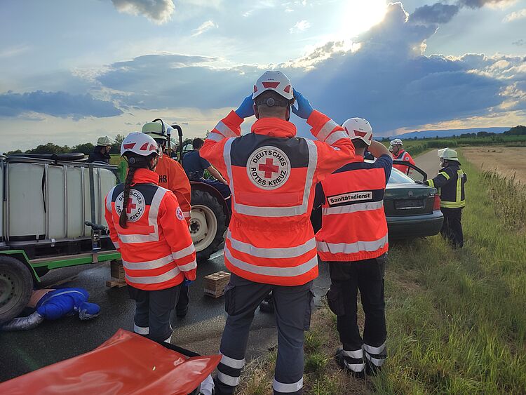 Drei DRK Einsatzkräfte leisten medizinische Hilfe bei einem Verkehrsunfall. 